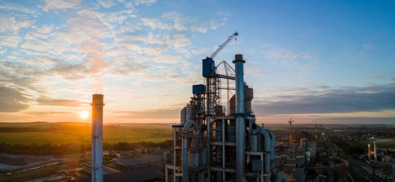 Aerial view of cement factory tower with high concrete plant structure at industrial production area. Manufacturing and global industry concept.