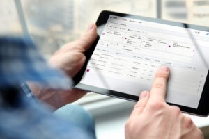 Mann, der Tablet auf dem das VAS Cloud Logistics Kundenportal geöffnet ist, in der Hand hält